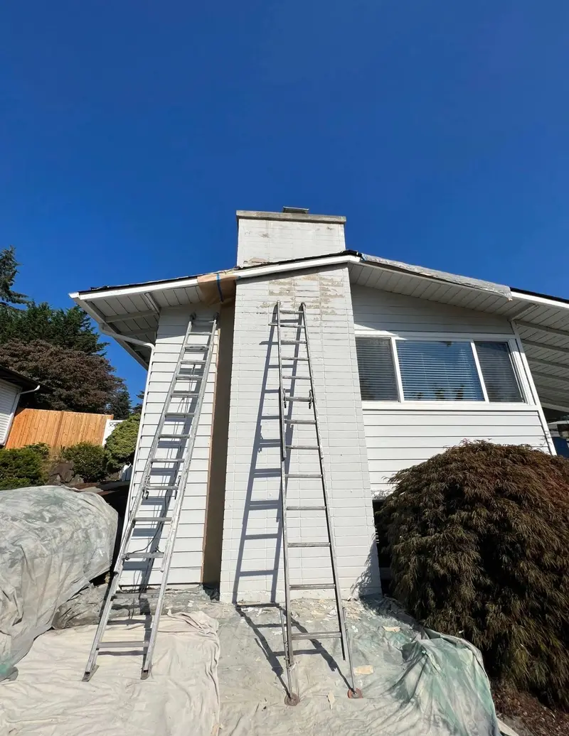 Ladder leaning against chimney during painting and maintenance service Seattle