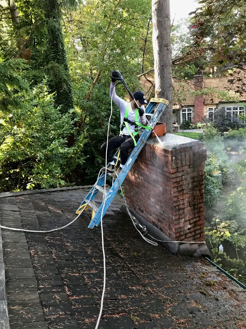 Technician power washing top of a chimney Seattle WA